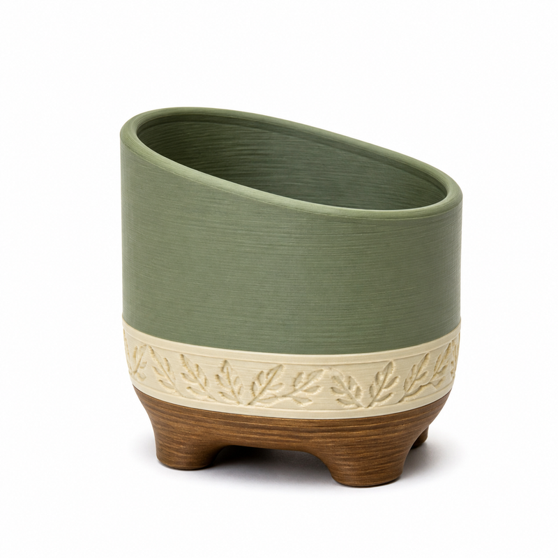 Product image of "Suitable plant pot with leaf frost" on white background: plant pot; Basic shape: slanted cylindrical vessel shape on three short feet; Design: a distinctive inclined opening and a circumferential relief band; Colours: sage green, cream and brown.