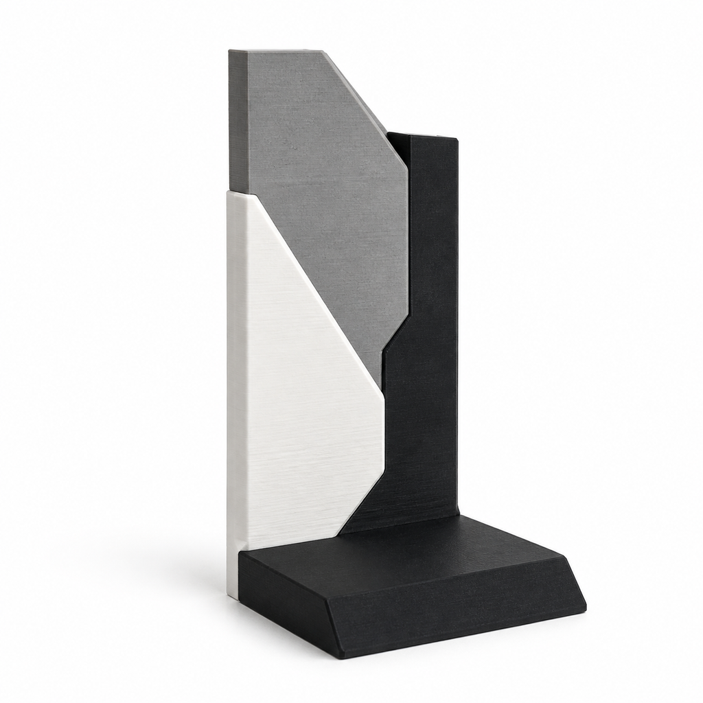 Product illustration of "Geometric bookend with diagonal fold" on a white background: bookend; Basic shape: right-angled support with high edged rear wall; Design: several oblique surfaces and an asymmetrical upper edge; Colours: white, grey and black.