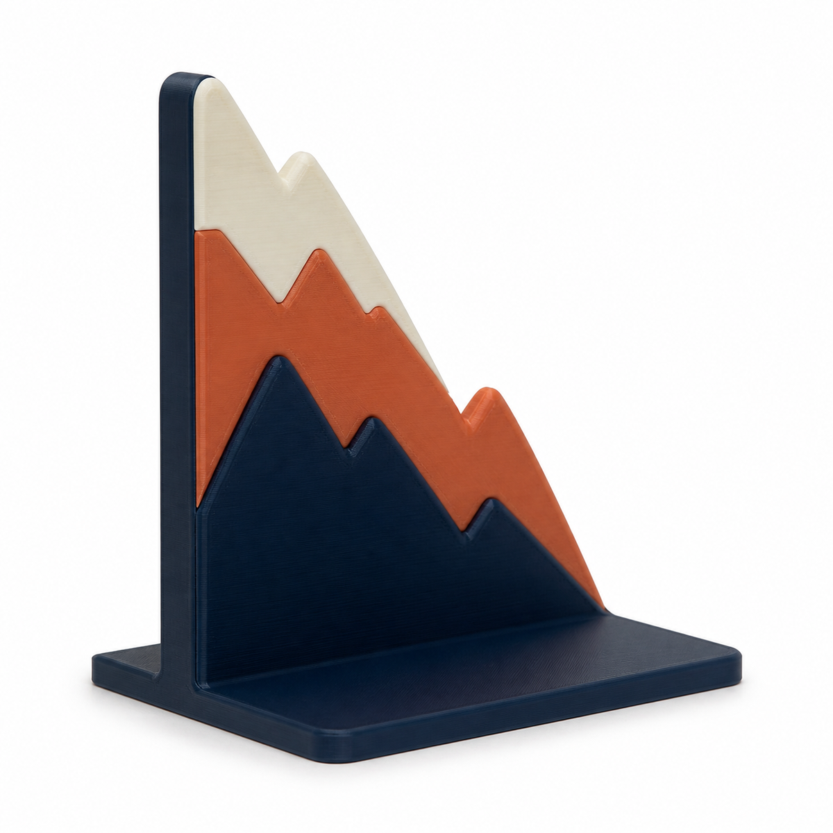 Product illustration by “bookend with abstract mountain silhouette” on a white background: bookend; Basic shape: rectangular support with staggered serrated height lines; Design: three superimposed mountain surfaces and a sharply rising rear wall; Colours: navy blue, terracotta and cream.