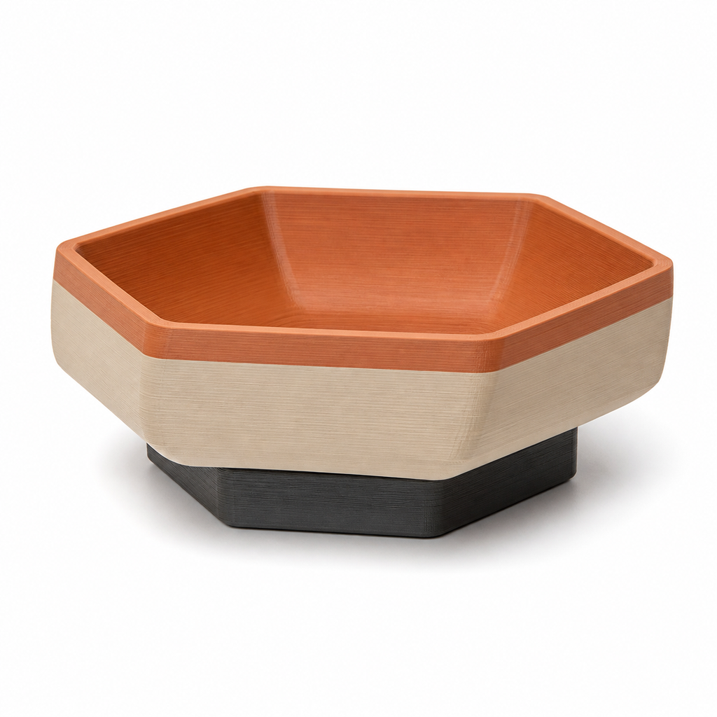 Product image of "Polygonal foot shell in terracotta and cream" on white background: decorative bowl; Basic shape: deep hexagonal shell shape on a dark polygonal foot; Design: wide quiet exterior surfaces and a slightly lowered inner recess; Colours: terracotta, cream and anthracite.