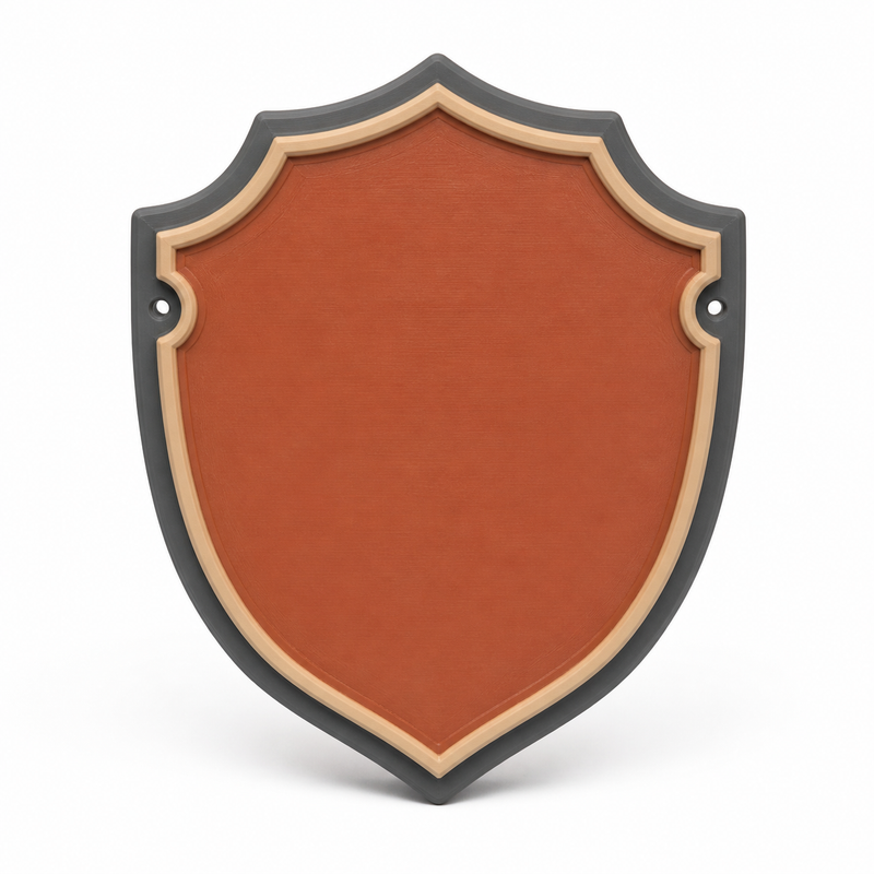 Product illustration by “Shield-shaped door sign in terracotta” on a white background: door sign; Basic shape: high downwards pointed coat of arms with two lateral eyes; Design: a curved cream-coloured inner frame and dark outer edge; Colours: terracotta, cream and anthracite.