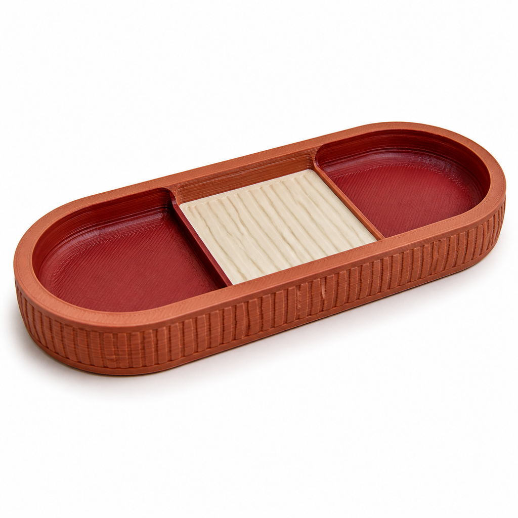 Product illustration of "Triple decorative tray in terracotta and red" on white background: decorative tray; Basic shape: elongated rounded shape with two red outer compartments and bright middle; Design: three clearly separated storage zones and a ribbed outer edge; Colours: terracotta, red and cream.