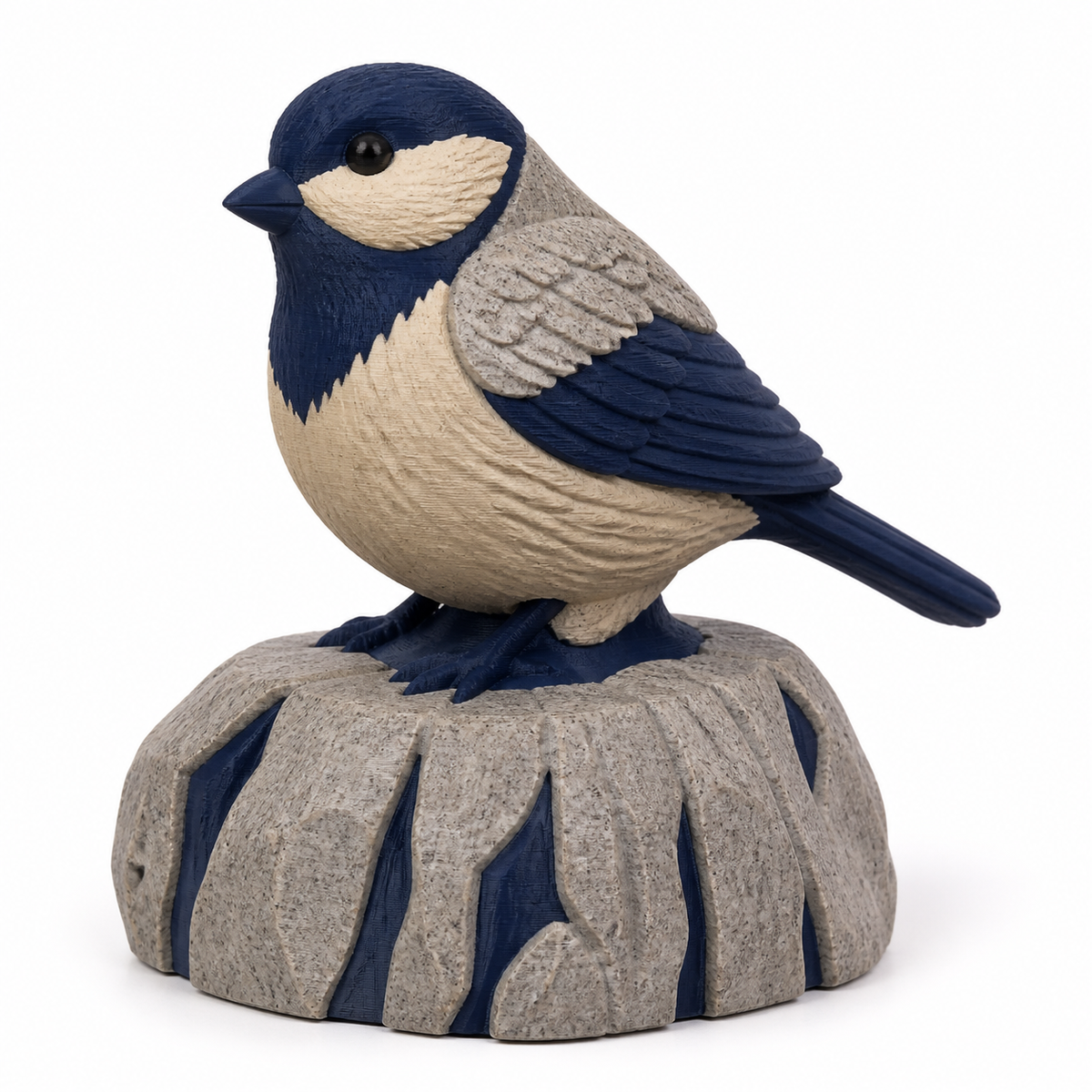 Product illustration of "bird figure on rocky pedestal" on white background: bird figure; Basic shape: seated small bird on a high coarsely furrowed round pedestal; Design: finely modeled wings, a light chest and angular rock gaps; Colours: navy blue, stone grey and beige.