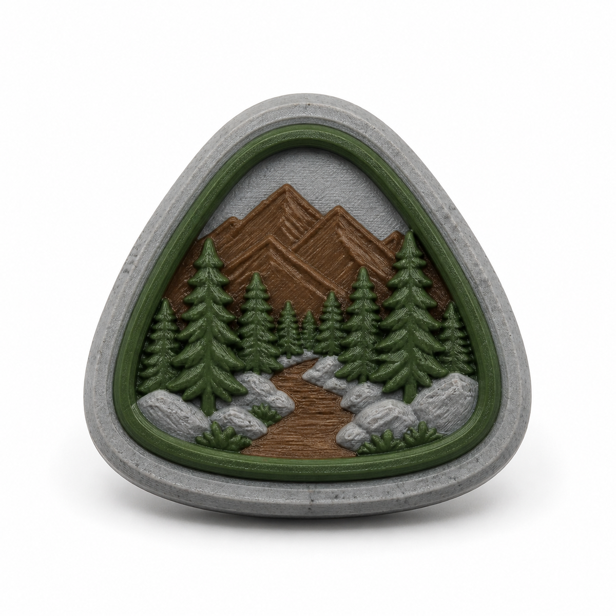 Dreieckiger Magnet mit Wald- und Bergmotiv – Produktansicht auf weißem Hintergrund; Farben: Steingrau, Dunkelgrün und Braun.