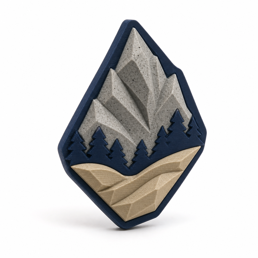 Rautenförmiger Magnet mit Bergpanorama – Produktansicht auf weißem Hintergrund; Farben: Navyblau, Steingrau und Beige.