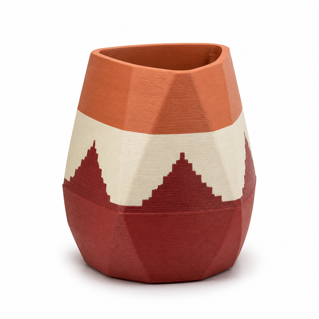 Product image of "Vase Gipfelglut" on white background: decorative vase; Basic shape: compact faceted body with slightly asymmetrical opening; Design: circumferential, jagged mountain band between large colour areas; Colours: terracotta, Dark red and cream.